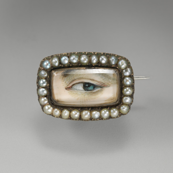 Broszka "Lover’s Eye" z początku XIX w., wykonana ze złota, ozdobiona kryształem przykrywającym rysunek oraz rzędem pereł; zdjęcie: MET, domena publiczna 