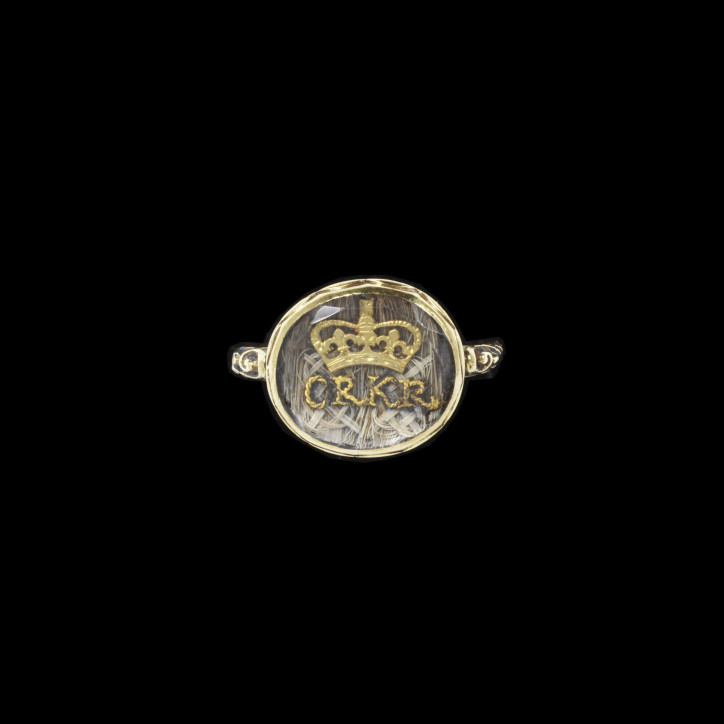 Pierścień żałobny upamiętniający Karola II i Katarzynę z Braganzy, ok. 1685–1705, ozdobiony owalnym fasetowanym kryształem przykrywającym splecione włosy oraz wykonane ze złotego drutu inicjały CR KR pod koroną; ©Victoria & Albert Museum, London