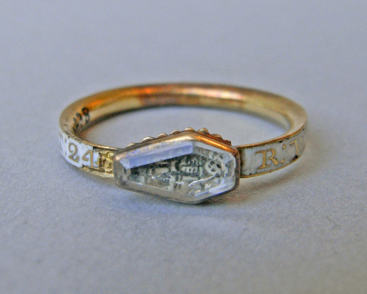 Pierścień żałobny z ok. 1724 r., wykonany ze złota, ozdobiony kryształem w kształcie trumny przykrywającym motyw czaszki i skrzyżowanych piszczeli. Obrączka ozdobiona napisem na emaliowanym na biało tle: „R.WENBORN OB.4.DEC.1724.AET.24”; © The Trustees of the British Museum CC BY-NC-SA 4.0