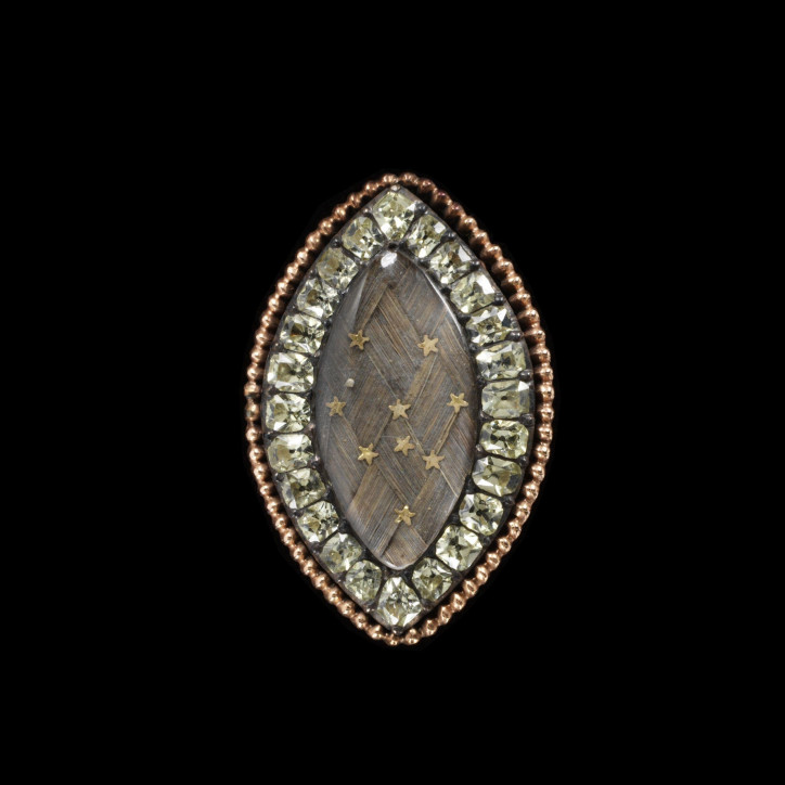 Pierścień żałobny, ok. 1760–1800, wykonany ze złota, ozdobiony chryzoberylami okalającymi kryształ w kształcie markizy przykrywający splecione włosy ozdobione ośmioma małymi złotymi gwiazdkami; ©Victoria & Albert Museum, London